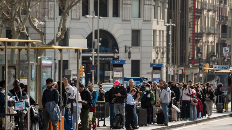Los turistas se reúnen en una estación de autobuses para trasladar hacia el aeropuerto el 14 de marzo de 2020 en Barcelona, España. (David Ramos/Getty Images)