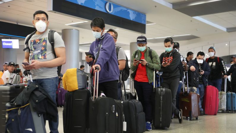La gente espera para registrarse en el mostrador de Qatar Airways en medio de los temores de coronavirus en el Aeropuerto Internacional de Miami, el 15 de marzo de 2020, en Miami, Florida. (Joe Raedle/Getty Images)