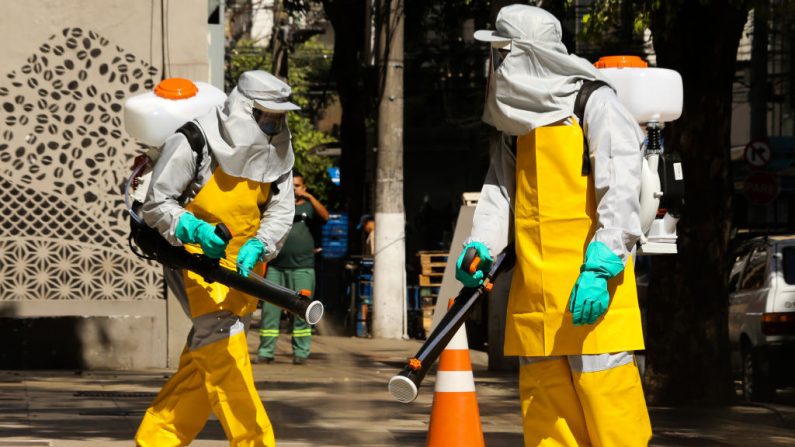Miembros de un equipo de limpieza vestidos con trajes protectores rocían lugares públicos con una solución desinfectante en el barrio de Icarai el 23 de marzo de 2020 en Niteroi, Brasil. (Luis Alvarenga/Getty Images)