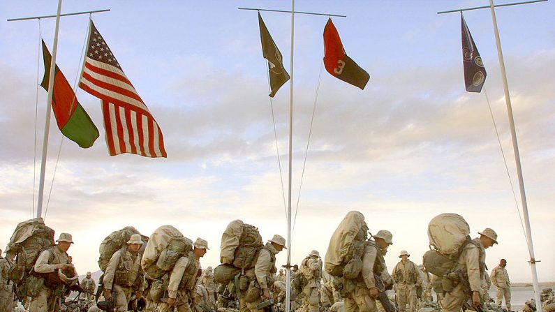 La compañía de Marines de EE.UU. marcha con su equipo mientras se prepara para salir del complejo militar estadounidense en el aeropuerto de Kandahar el 22 de enero de 2002 en Kandahar, Afganistán. (Mario Tama/Getty Images)