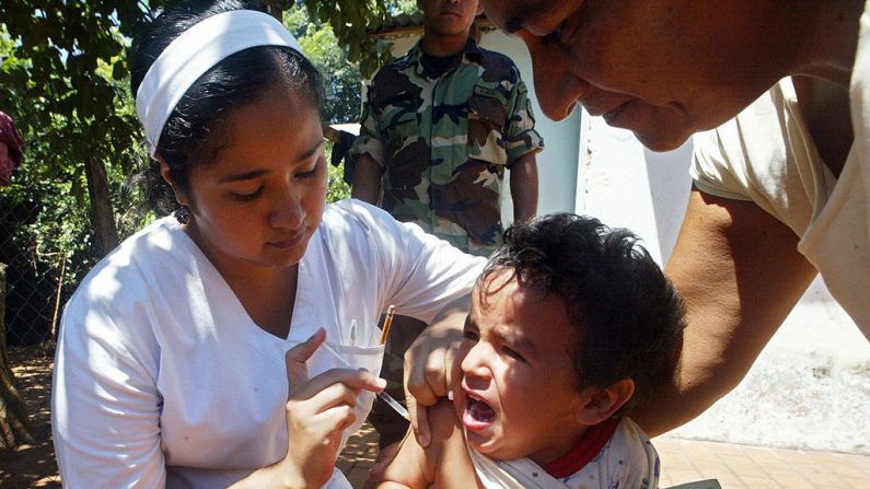 Un trabajador del Ministerio de Salud está vacunando a un niño contra la fiebre amarilla y el dengue en Laurelty, un barrio de San Lorenzo, a 25 km al este de Asunción (Paraguay), el 14 de febrero de 2008. (NORBERTO DUARTE/AFP vía Getty Images)
