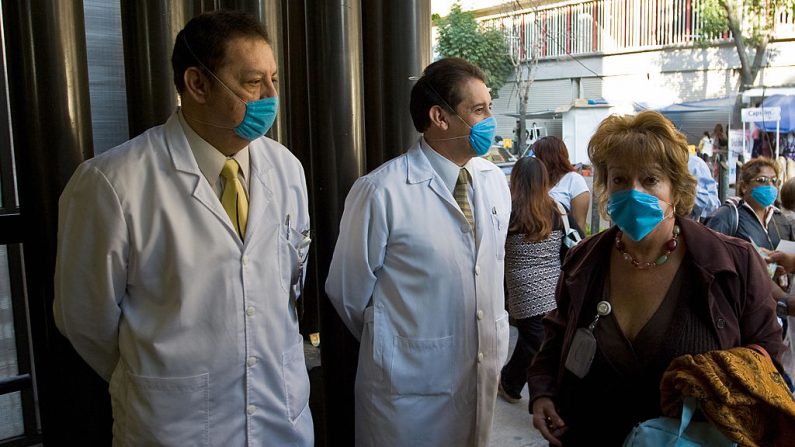Una mujer y dos médicos a la entrada de la sede de la empresa estatal Petróleos Mexicanos (PEMEX) en la Ciudad de México (México) el 27 de abril de 2009. (Ronaldo Schemidt/AFP a través de Getty Images)