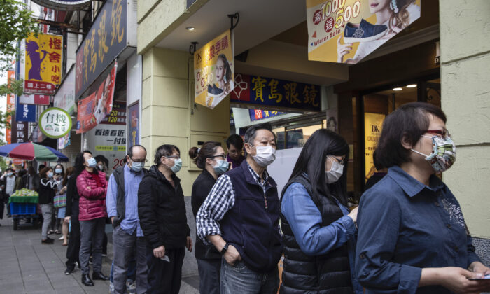 Personas hacen fila frente a una farmacia para recoger máscaras encargadas por Internet, en Taipei, Taiwán, el 18 de marzo de 2020. (Paula Bronstein/Getty Images )