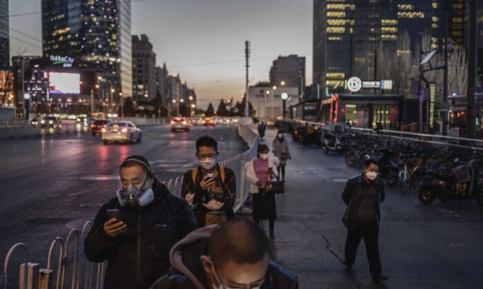 Viajeros chinos llevan máscaras protectoras mientras hacen fila esperando un autobús, en Beijing, el 20 de marzo de 2020. (Kevin Frayer/Getty Images)