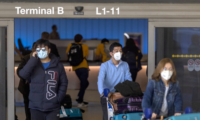 Los viajeros llegan a la Terminal Internacional Tom Bradley, de LAX, con máscaras médicas para protegerse contra el nuevo brote de coronavirus en Los Ángeles, California, el 2 de febrero de 2020. (David McNew/Getty Images)