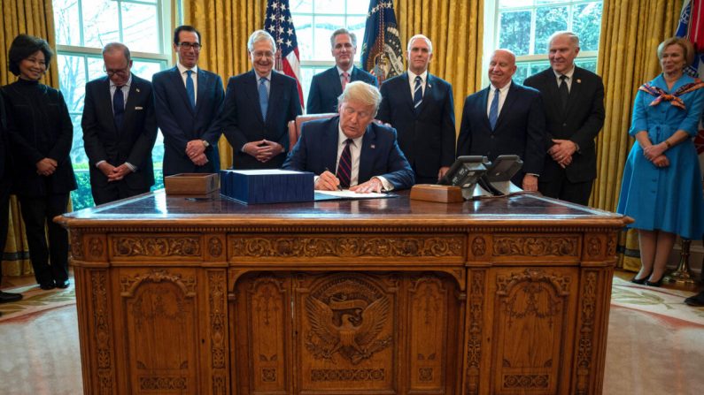 El presidente Donald Trump firma la ley CARES, un paquete de rescate de USD 2.2 billones para proporcionar alivio económico en medio del brote del virus del PCCh, en la Oficina Oval de la Casa Blanca el 27 de marzo de 2020. (Jim Watson/AFP a través de Getty Images)