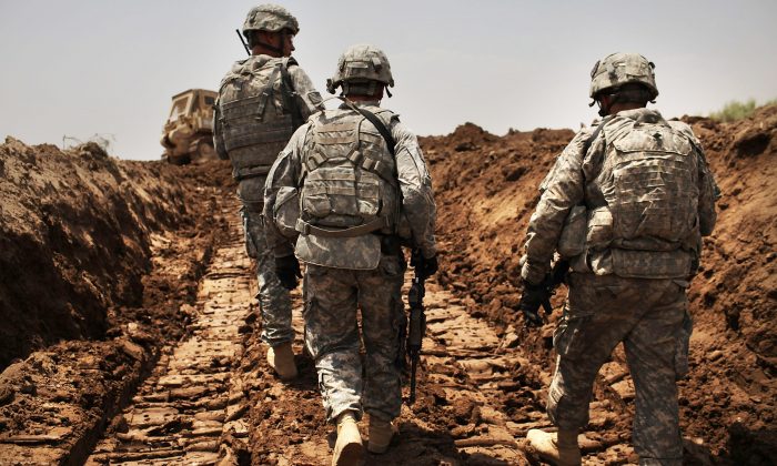 Soldados estadounidenses del 3er Regimiento de Caballería Blindada patrullan una nueva zanja que han cavado para proteger la base de un ataque en Iskandariya, provincia de Babil, Irak, el 19 de julio de 2011. (Spencer Platt/Getty Images)