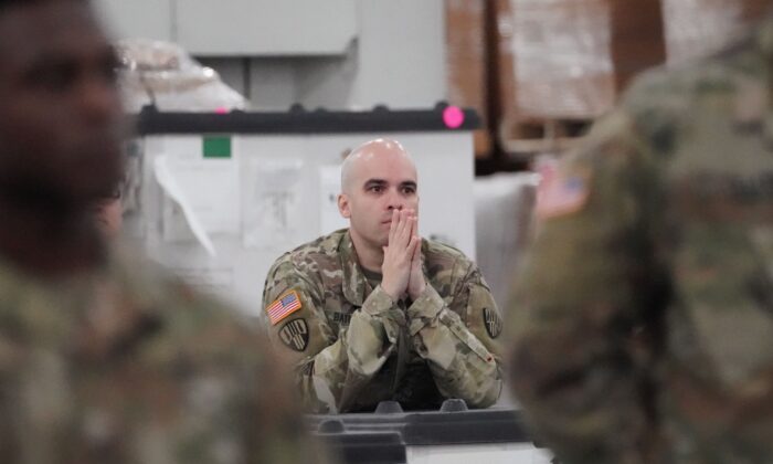 Miembros de la Guardia Nacional del Ejército de EE.UU. escuchan al gobernador de Nueva York, Andrew Cuomo, anunciando planes para convertir un centro de conferencias en un hospital de campaña, en la ciudad de Nueva York, el 23 de marzo de 2020. (Bryan R. Smith/AFP/Getty Images)