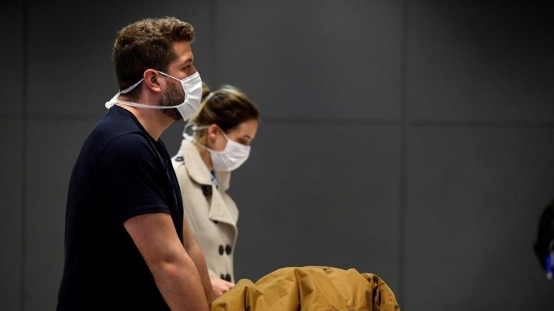 Una pareja protegida con tapabocas, como medida de precaución contra la propagación del virus COVID-19, fue registrada el 16 de marzo de 2020 en el Aeropuerto Internacional de Sao Paulo (Brasil). EFE/Sebastião Moreira
