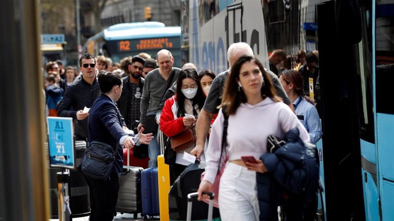 Turistas aguardan ante el autobús del aeropuerto en Barcelona, España, para volver a casa el 14 de marzo de 2020. EFE/Alberto Estévez