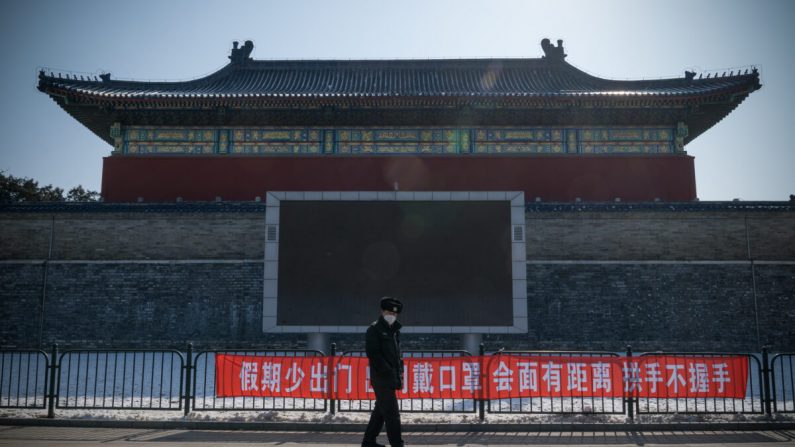 Un guardia de seguridad pasa junto a una pancarta de propaganda que dice "No salga de casa a menudo durante las vacaciones, use una máscara al salir, mantenga la distancia y no se dé la mano al reunirse" en el Parque del Templo del Cielo, Beijing, China, el 15 de febrero. 2020. (Andrea Verdelli/Getty Images)
