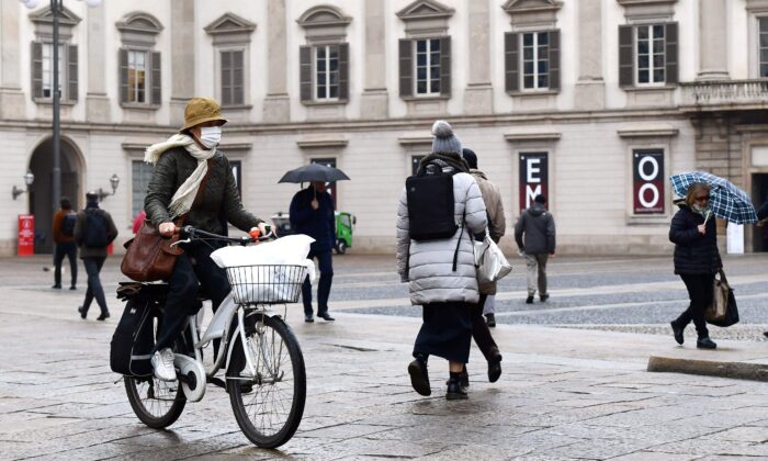 Una mujer con una mascarilla protectora cruza la Piazza Duomo con su bicicleta en Milán el 2 de marzo de 2020. (Miguel Medina/AFP vía Getty Images)