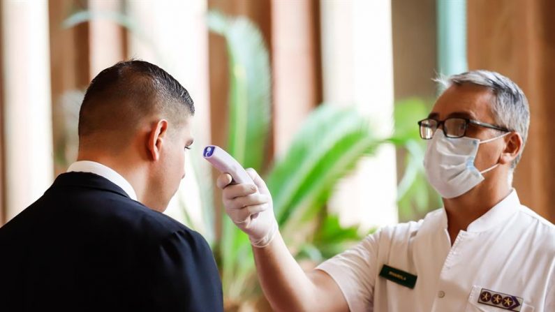 Un médico militar fue registrado este lunes al tomarle la temperatura a un visitante al Palacio de Gobierno, en Asunción (Paraguay). EFE/Nathalia Aguilar
