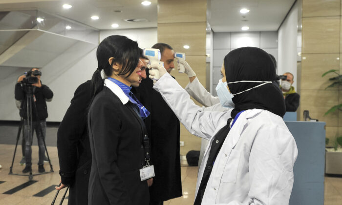 Trabajadores sanitarios egipcios escanean las temperaturas corporales de la gente en el Aeropuerto Internacional de El Cairo el 1 de febrero de 2020. (AFP vía Getty Images)