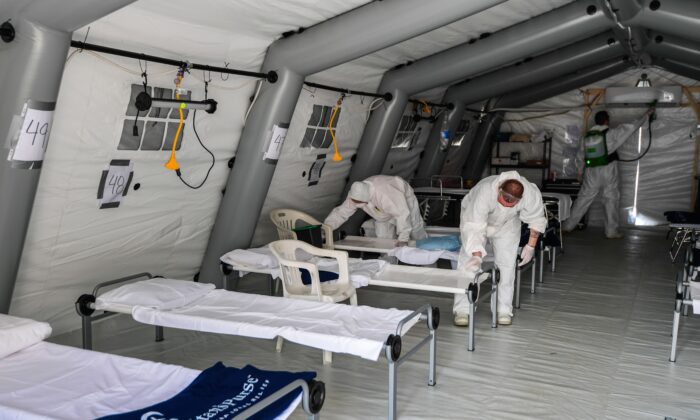 Trabajadores desinfectan una tienda de campaña en un hospital de campo para pacientes con el virus del PCCh en Cremona, Italia, el 20 de marzo de 2020. (Miguel Medina/AFP vía Getty Images)