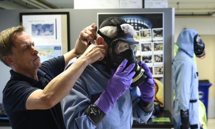 Un hombre se prueba un traje impregnado de carbón permeable, combinado con un respirador (o máscara antigás), botas de goma y tres capas de guantes durante un simulacro en la sede de la OPCW (Organización para la Prohibición de las Armas Químicas) en La Haya, Países Bajos, el 20 de abril de 2017. (John Thys/AFP vía Getty Images)