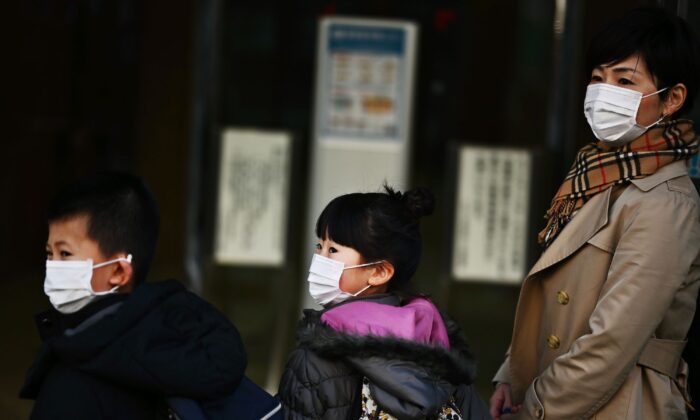 Una mujer japonesa, su hija y su hijo llegan a su lugar de trabajo en Tokio el 6 de marzo de 2020. (Charly Triballeau/AFP vía Getty Images)