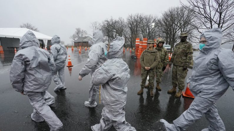 Trabajadores en trajes protectores se preparan mientras esperan a que las personas se sometan a pruebas al llegar en coche al primer recorrido del estado por el laboratorio de pruebas móvil de COVID-19 en Glen Island Park en New Rochelle, Nueva York, el 13 de marzo de 2020. (Timothy A. Clary/AFP vía Getty Images)