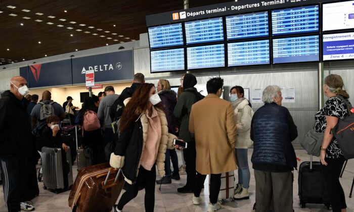 Un viajero con una máscara facial pasa al lado de otro parado frente a las pantallas que muestran los horarios de los vuelos en el aeropuerto de París después de que el presidente de los Estados Unidos, Donald Trump, anunciara la prohibición de viajar por el nuevo coronavirus, el 12 de marzo de 2020. (Bertrand Guay/AFP vía Getty Images)
