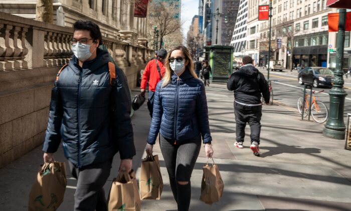 Residentes de Nueva York llevan comestibles con máscaras y guantes el 14 de marzo de 2020. (Apu Gomes/AFP vía Getty Images)