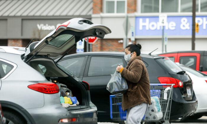 Una mujer con una máscara facial carga sus compras en un su auto en un estacionamiento de Walmart en Columbus, Ohio, el 20 de marzo de 2020. (Charlotte Cuthbertson/The Epoch Times)