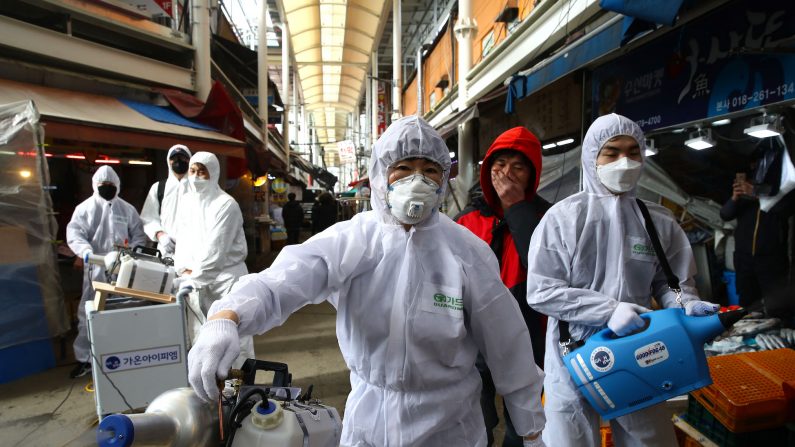 Profesionales de la desinfección que usan equipo de protección rocían solución antiséptica contra el coronavirus en un mercado tradicional en Seúl, Corea del Sur, el 26 de febrero de 2020. (Chung Sung-Jun/Getty Images)