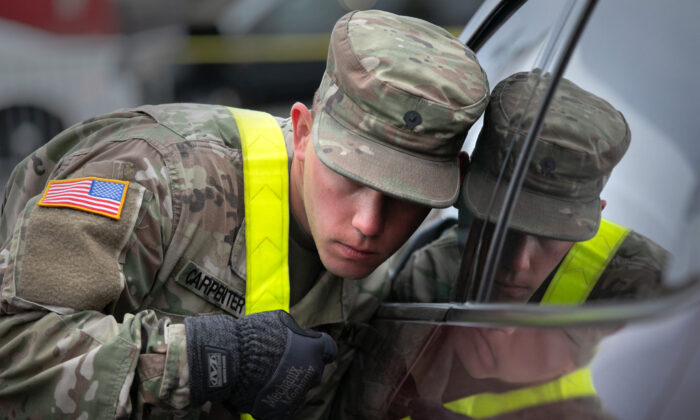 Un soldado de la Guardia Nacional de EE. UU. escucha a un paciente en un centro de pruebas de virus del PCCh en el Lehman College de la ciudad de Nueva York el 28 de marzo de 2020. (John Moore/Getty Images)
