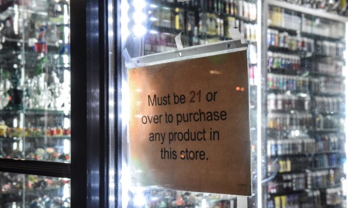 Un cartel que dice "debe ser mayor de 21 años" cuelga en la ventana de una tienda de artículos para vapeo en la Ciudad de Nueva York el 19 de diciembre de 2019. (Stephanie Keith/Getty Images)