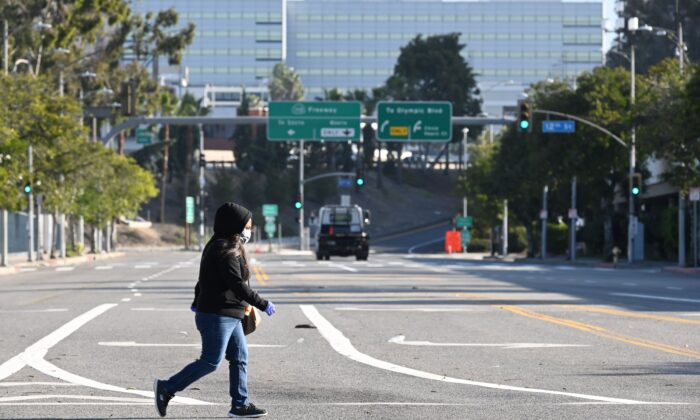 Una mujer cruza una calle vacía cerca del Centro de Convenciones de Los Ángeles, California, el 30 de marzo de 2020. (Robyn Beck/AFP vía Getty Images)