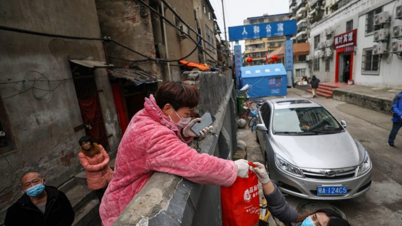 Un residente (centro I) recibe una bolsa de comida sobre un muro en Wuhan en la provincia central de Hubei en China el 3 de marzo de 2020. (STR/AFP vía Getty Images)
