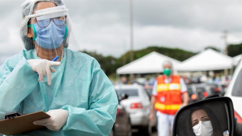 Trabajadores sanitarios fueron registrados al realizarle pruebas rápidas de COVID-19 a ciudadanos en sus automóviles, habilitadas por el gobierno de Brasilia (Brasil). EFE/Joédson Alves
