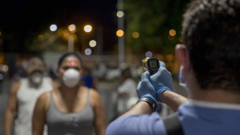 Un doctor toma la temperatura a una mujer como medida de prevención ante el covid-19, durante una velada de boxeo organizada por la promotora Búfalo Boxing Promotions, en las instalaciones del polideportivo Alexís Arguello en Managua (Nicaragua). EFE/Jorge Torres
