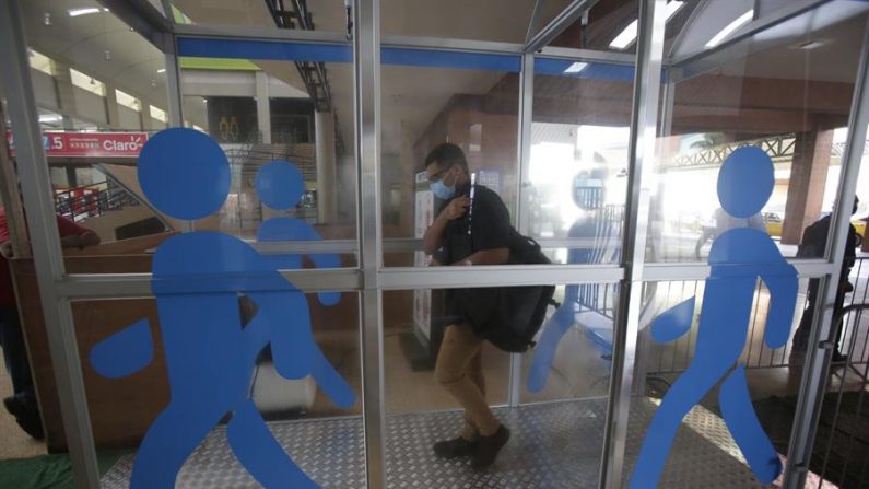 Usuarios pasan por una cabina de desinfección instalada en la terminal de autobuses más importante del país en Ciudad de Panamá. EFE/Carlos Lemos
