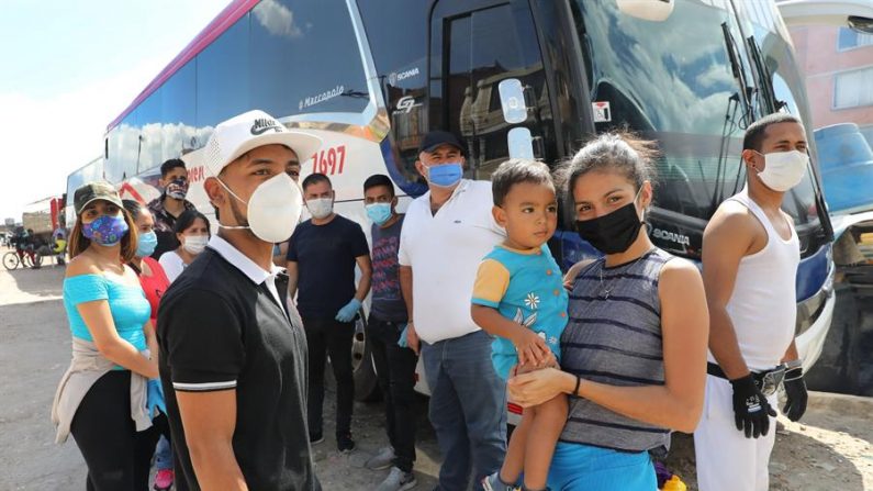 Un grupo de ciudadanos venezolanos fue registrado este domingo, junto a los buses que fueron rentados por ellos mismos para regresar a su país ante la pandemia de la COVID-19, pero que fueron devueltos por las autoridades colombianas, en Bogotá (Colombia). EFE/Carlos Ortega
