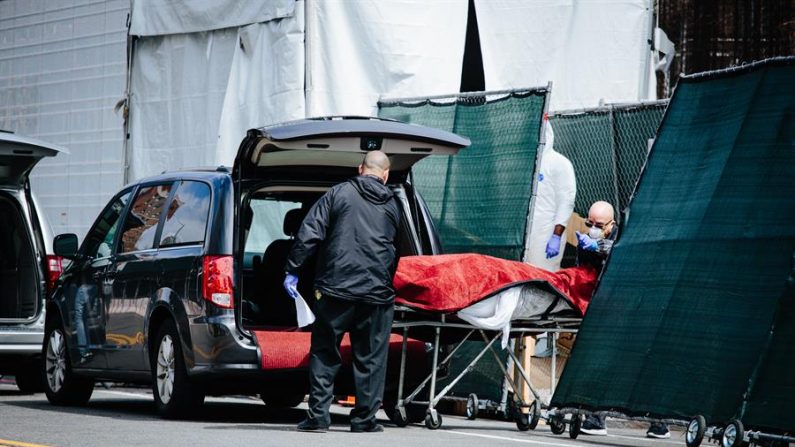 Empleados del hospital y de los servicios funerarios trasladan un cuerpo desde una morgue móvil temporal, instalada por falta de espacio en el hospital, a un vehículo de la funeraria en las afueras del Centro Hospitalario de Brooklyn en Brooklyn, Nueva York, EE.UU., 08 de abril de 2020. EFE/Alba Vigaray
