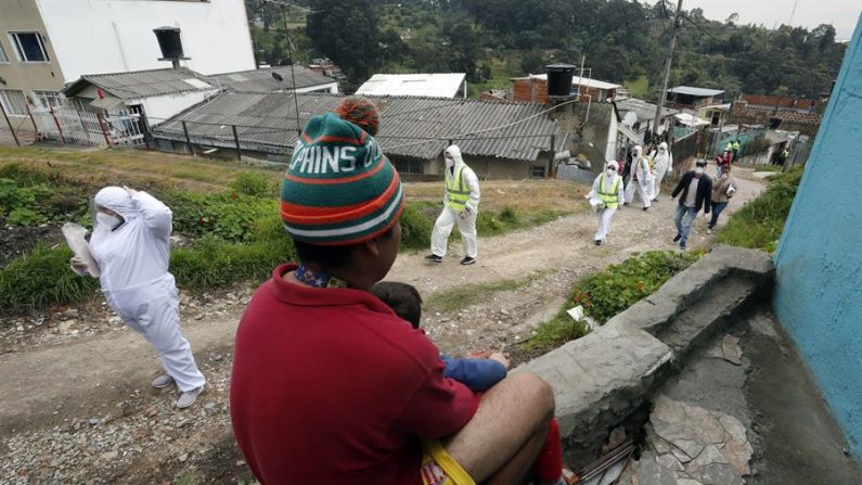 Trabajadores de la Alcaldía de Bogotá fueron registrados a su llegada al barrio Bosque Calderón, en una de las laderas de la capital colombiana, a entregar ayudas alimentarias a familias de bajos recursos durante el confinamiento social obligatorio por la pandemia del COVID-19. EFE/Mauricio Dueñas Castañeda
