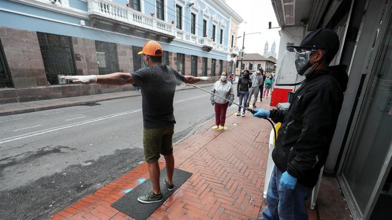 Un empleado desinfecta a un ciudadano antes de entrar a un supermercado en Quito (Ecuador). EFE/José Jácome
