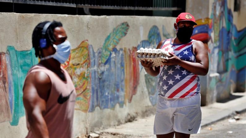 Un hombre con tapabocas carga el 20 de abril de 2020 dos paquetes de huevos, en La Habana (Cuba). EFE/Ernesto Mastrascusa