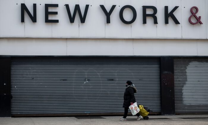 Una mujer usando mascarilla pasa por delante de una tienda cerrada en el barrio Astoria de Queens, Nueva York, el 15 de abril de 2020. (Johannes Eisele/AFP vía Getty Images)