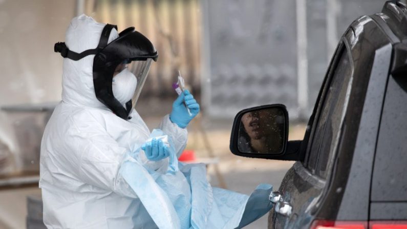 Una enfermera vestida con equipo de protección personal se prepara para dar una prueba COVID-19 con hisopo en una estación de pruebas en Stamford, Connecticut, el 23 de marzo de 2020. (John Moore/Getty Images)
