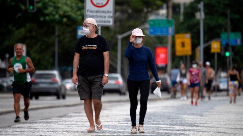 La gente usa mascarillas contra la propagación del virus del PCCh mientras camina en Río de Janeiro, Brasil, el 18 de abril de 2020, en medio del nuevo brote de COVID-19. (MAURO PIMENTEL/AFP vía Getty Images)