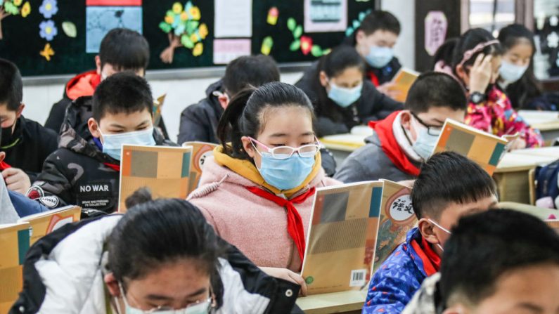 Los estudiantes de la escuela primaria que llevan máscaras faciales asisten a una clase cuando regresan a la escuela después de que el comienzo del trimestre se retrasara debido al brote del virus del PCCh, en Huaian, en la provincia oriental de Jiangsu de China, el 7 de abril de 2020. (STR/AFP vía Getty Images)
