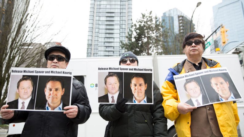Manifestantes sostienen fotos de los canadienses Michael Spavor y Michael Kovrig, que fueron detenidos por el régimen chino, fuera de la Corte Suprema de la Columbia Británica en Vancouver, mientras la directora financiera de Huawei, Meng Wanzhou, comparece ante la corte el 6 de marzo de 2019. (JASON REDMOND/AFP a través de Getty Images)