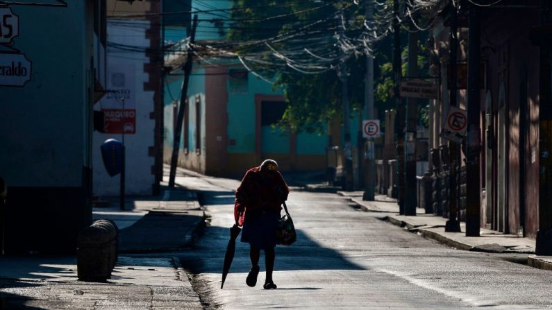 Una mujer camina por una calle vacía con una máscara facial en Tegucigalpa, Honduras, el 12 de abril de 2020 durante el toque de queda ordenado por el gobierno hondureño para ayudar a frenar la propagación del virus del PCCh. (ORLANDO SIERRA/AFP vía Getty Images)