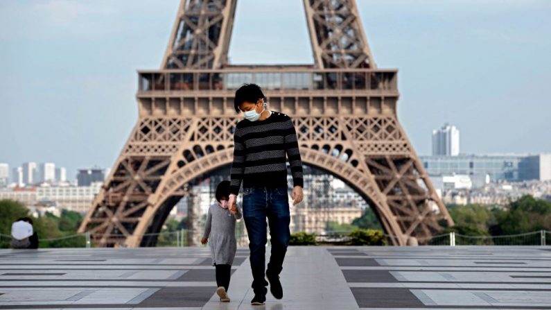 Un hombre y su hija con una máscara facial caminan por la vacía explanada del Trocadero cerca de la Torre Eiffel en París, Francia, el 20 de abril de 2020. (THOMAS COEX/AFP vía Getty Images)