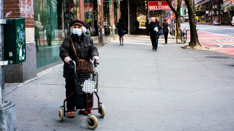 Una anciana usa una máscara y guantes de plástico mientras espera para cruzar la calle el 26 de marzo de 2020 en la ciudad de Nueva York, EE.UU. (Eduardo Muñoz Álvarez/Getty Images)