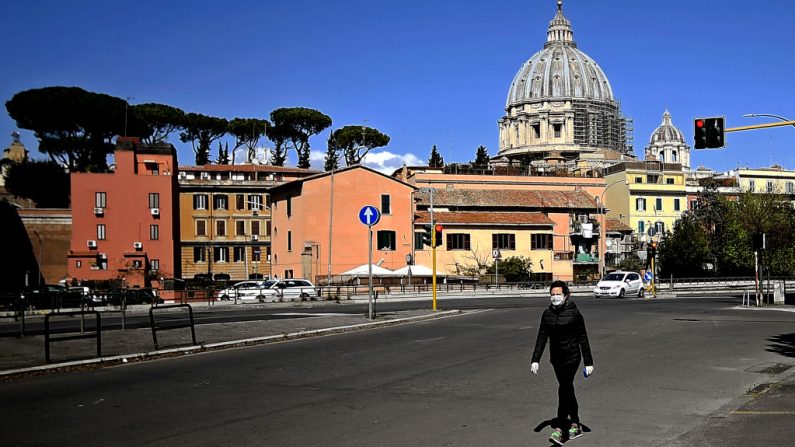 Una mujer camina por la Basílica de San Pedro al fondo en Roma, Italia, el 6 de abril de 2020, durante el encierro del país para frenar la propagación del virus del PCCh. (FILIPPO MONTEFORTE/AFP vía Getty Images)