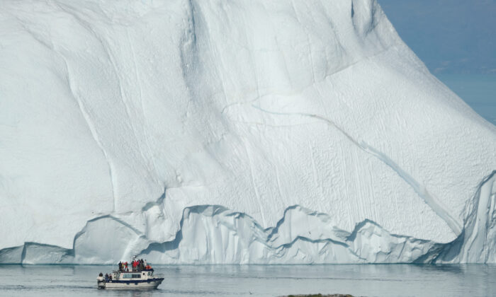 Un barco que transporta a los turistas pasando por un iceberg, en la desembocadura del fiordo de hielo de Ilulissat, Groenlandia, el 30 de julio de 2019. (Sean Gallup/Getty Images)
