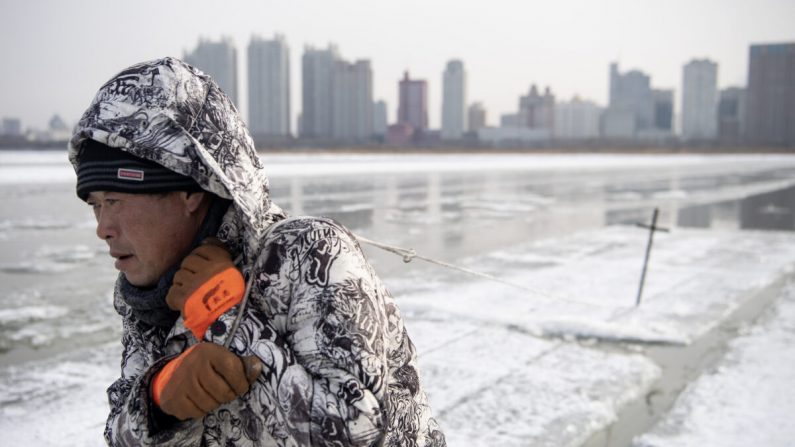 Un trabajador arrastra bloques de hielo en el río Songhua congelado en Harbin, China, el 11 de diciembre de 2019. (NOEL CELIS/AFP a través de Getty Images)