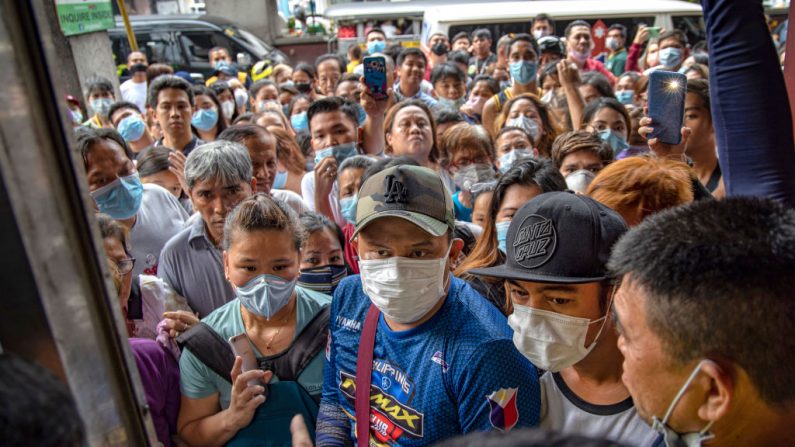 Filipinos que esperan comprar mascarillas se aglomeran frente a una tienda de suministros médicos que fue allanada por la policía por, supuestamente, acaparar y sobrevalorar las mascarillas, a medida que crecía el temor público por el virus del PCCh, el 31 de enero de 2020, en Manila, Filipinas. (Ezra Acayan/Getty Images)